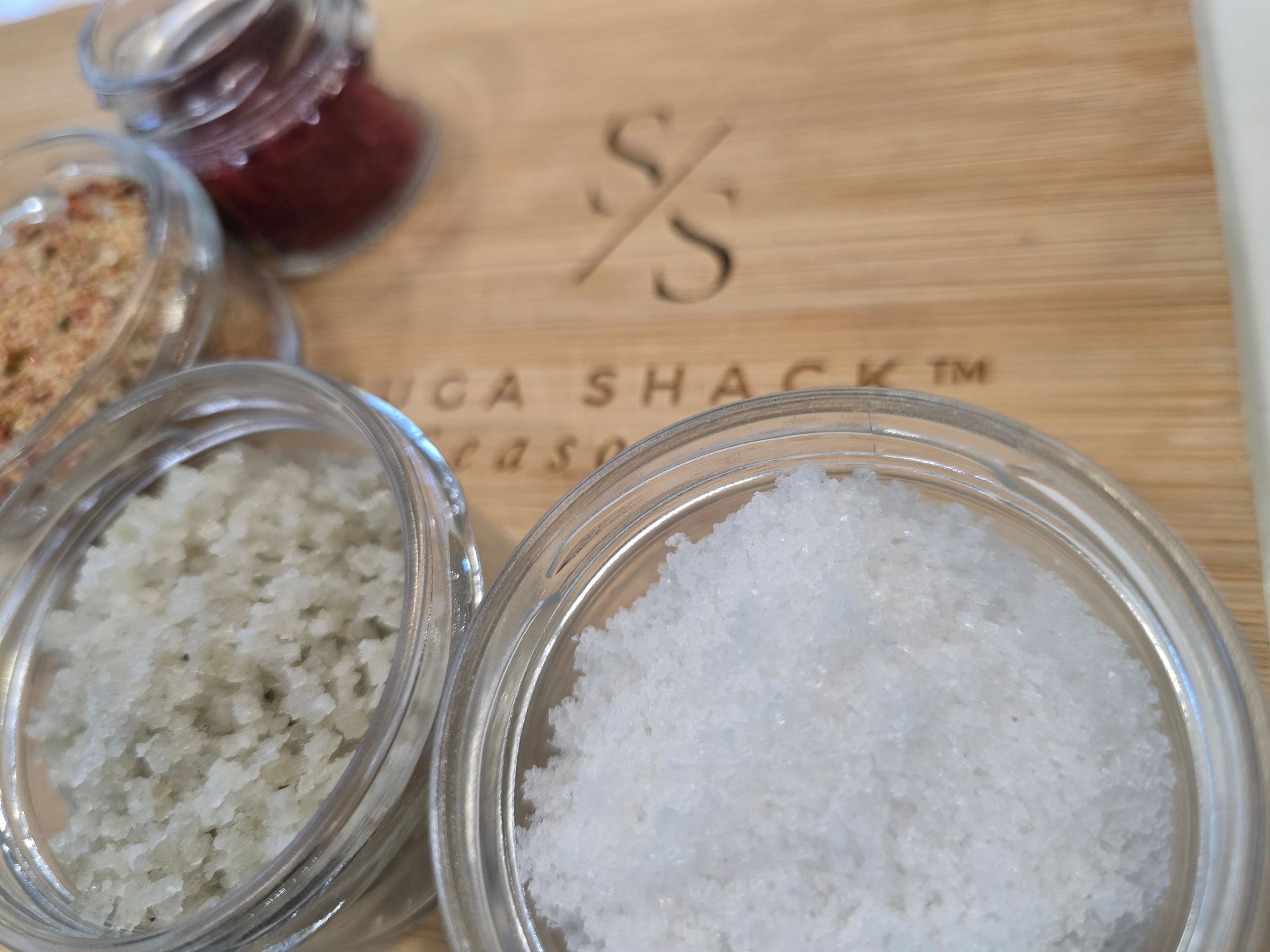 Wooden board with various salts in small glass jars.