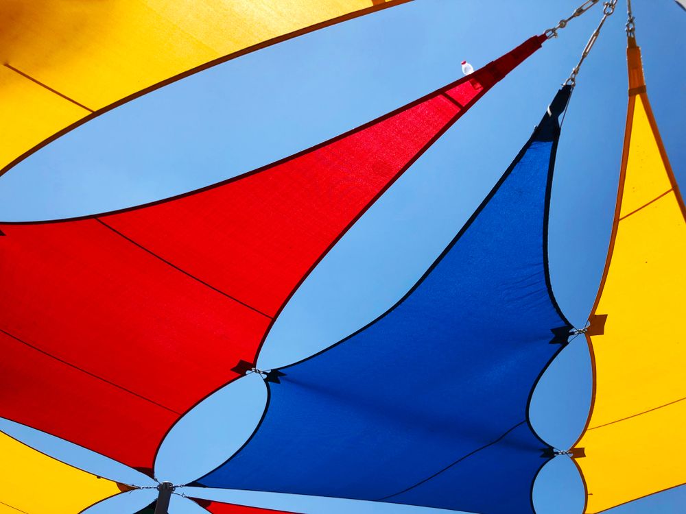 A Blue Red and Yellow Umbrella With Chains Hanging From It — Cooloola Sail Company In Pomona, QLD
