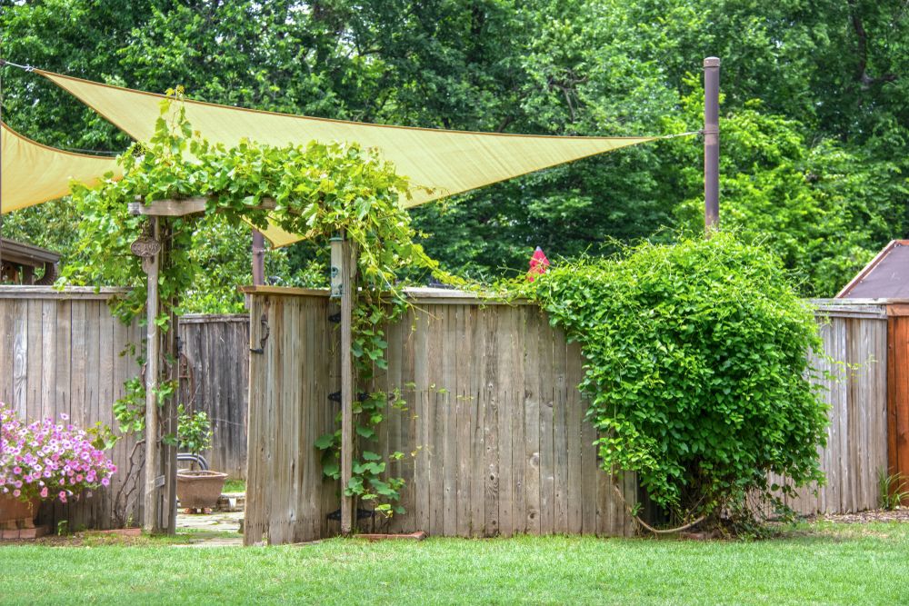 A Wooden Fence With a Yellow Sail Hanging Over It — Cooloola Sail Company In Eumundi, QLD
