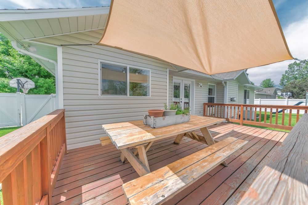 A Wooden Deck With a Picnic Table and Benches Under an Umbrella — Cooloola Sail Company In Pomona, QLD