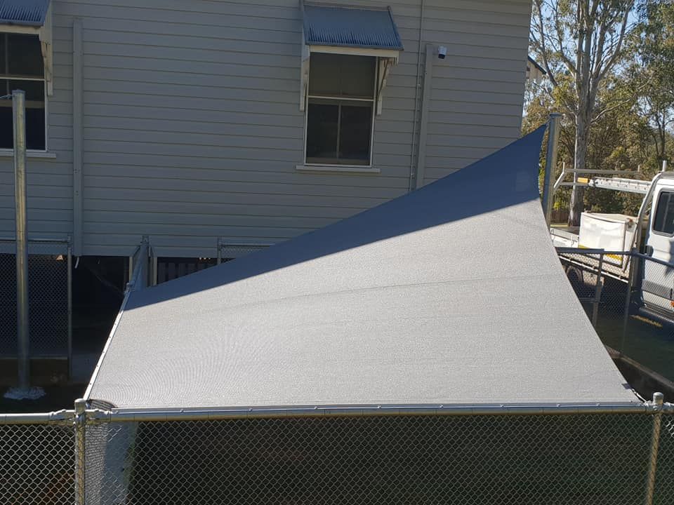 A White and Blue Shade Sail is Sitting in Front of a House — Cooloola Sail Company In Tin Can Bay, QLD