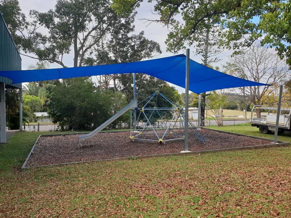A Blue Umbrella is Covering a Playground With a Slide — Cooloola Sail Company In Cooloola Cove, QLD