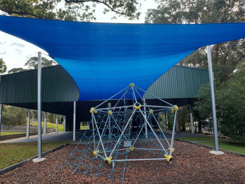 A Blue Shade Sail is Covering a Playground With a Climbing Net — Cooloola Sail Company In Southside, QLD