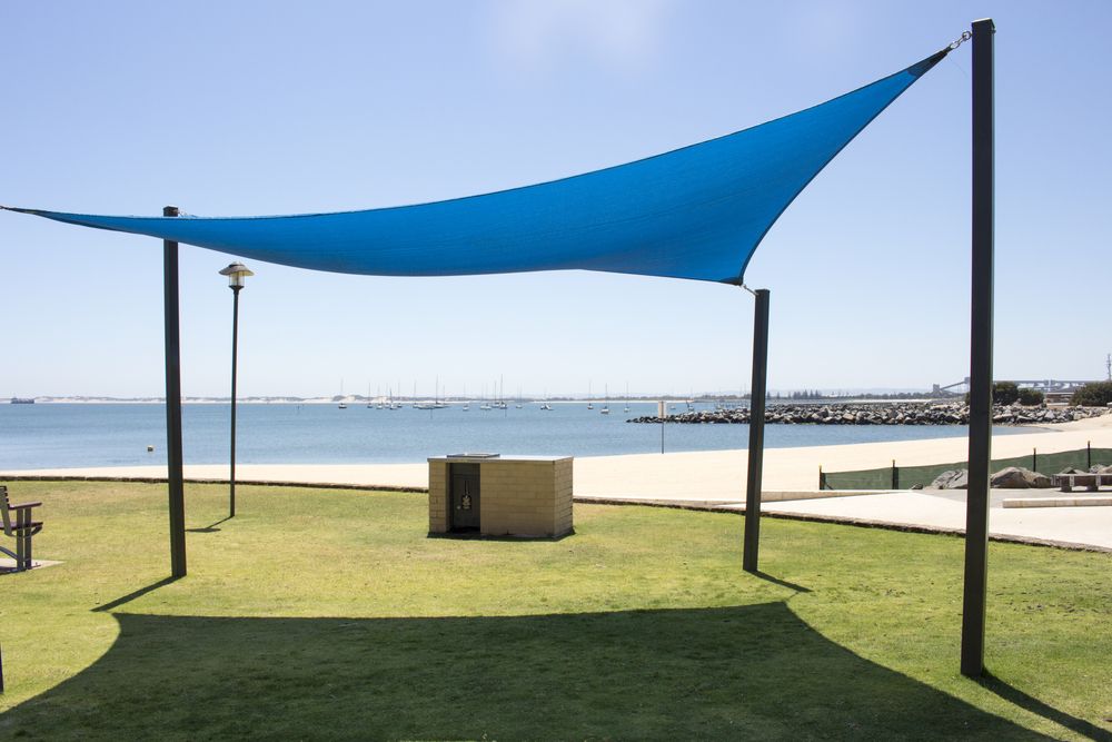 A Blue Umbrella is Sitting in the Grass Near the Beach — Cooloola Sail Company In Southside, QLD
