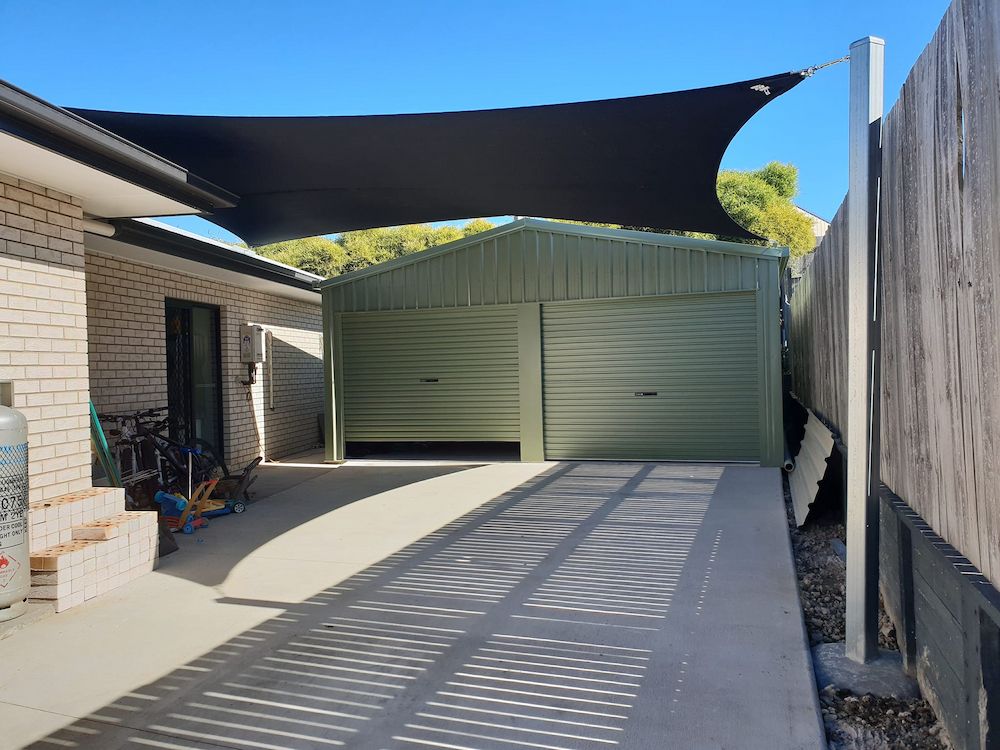 A Black Shade Sail is Hanging Over a Driveway Leading to a Garage — Cooloola Sail Company In Kilkivan, QLD