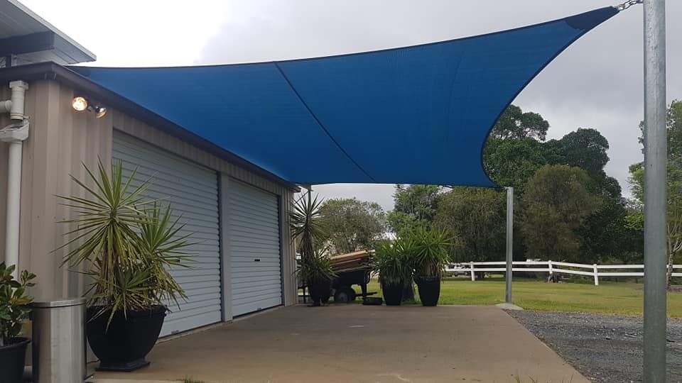 A Blue Shade Sail is Covering a Driveway in Front of a Garage — Cooloola Sail Company In Rainbow Beach, QLD