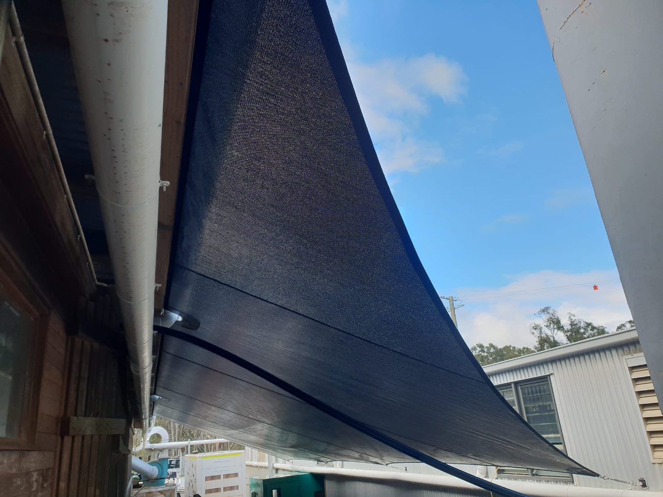 A Black Shade Sail is Hanging From the Side of a Building — Cooloola Sail Company In Tin Can Bay, QLD