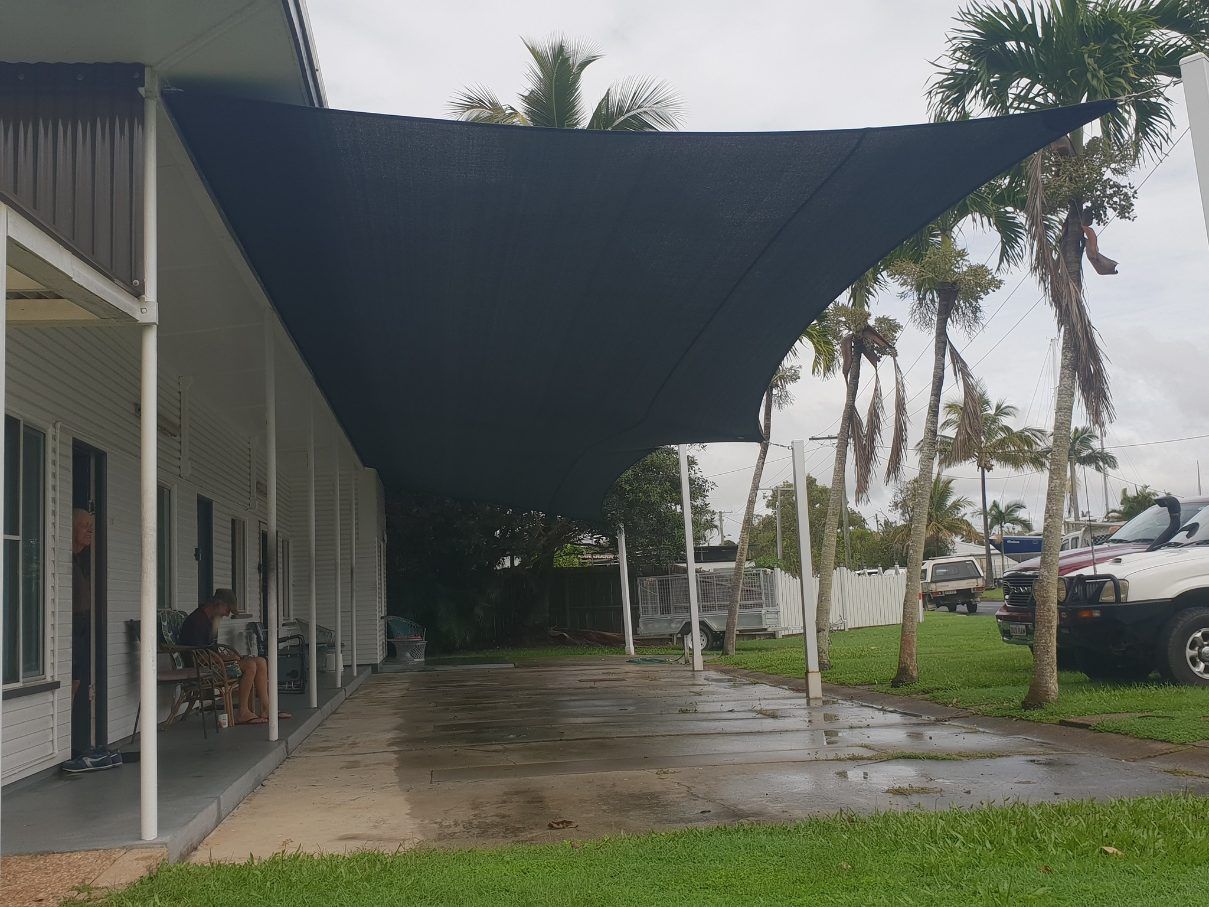 A Black Shade Sail is Covering a Driveway in Front of a House — Cooloola Sail Company In Tamaree, QLD