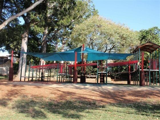 A Playground in a Park With a Blue Umbrella Over It — Cooloola Sail Company In Curra, QLD