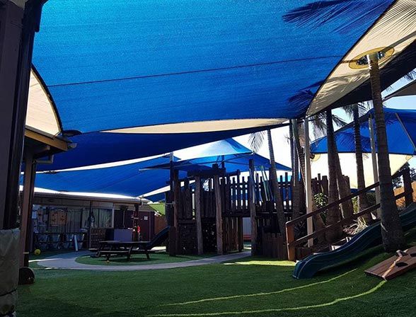 A Playground With Blue Umbrellas and a Slide — Cooloola Sail Company In Glenwood, QLD