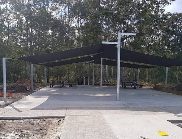 A Concrete Area With a Black Umbrella and Trees in the Background — Cooloola Sail Company In Glenwood, QLD