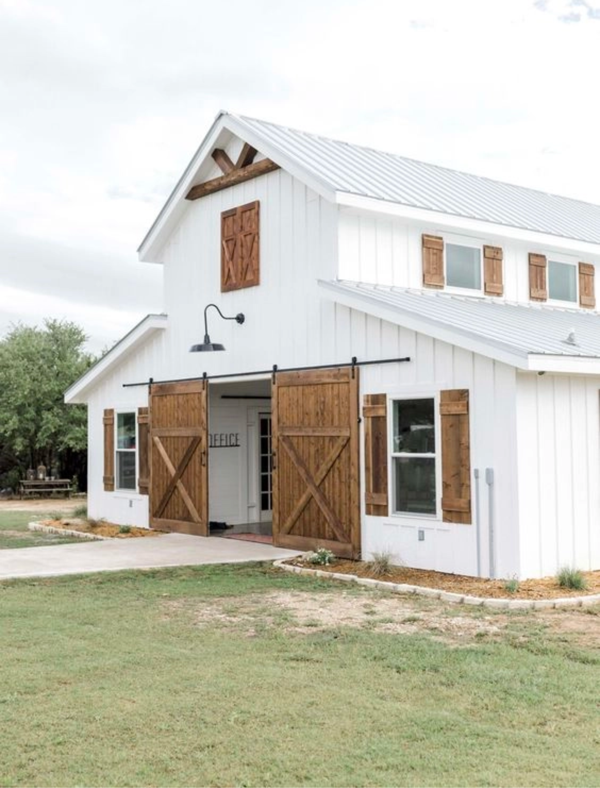 White Barndominium with gorgeous wooden sliding barn doores