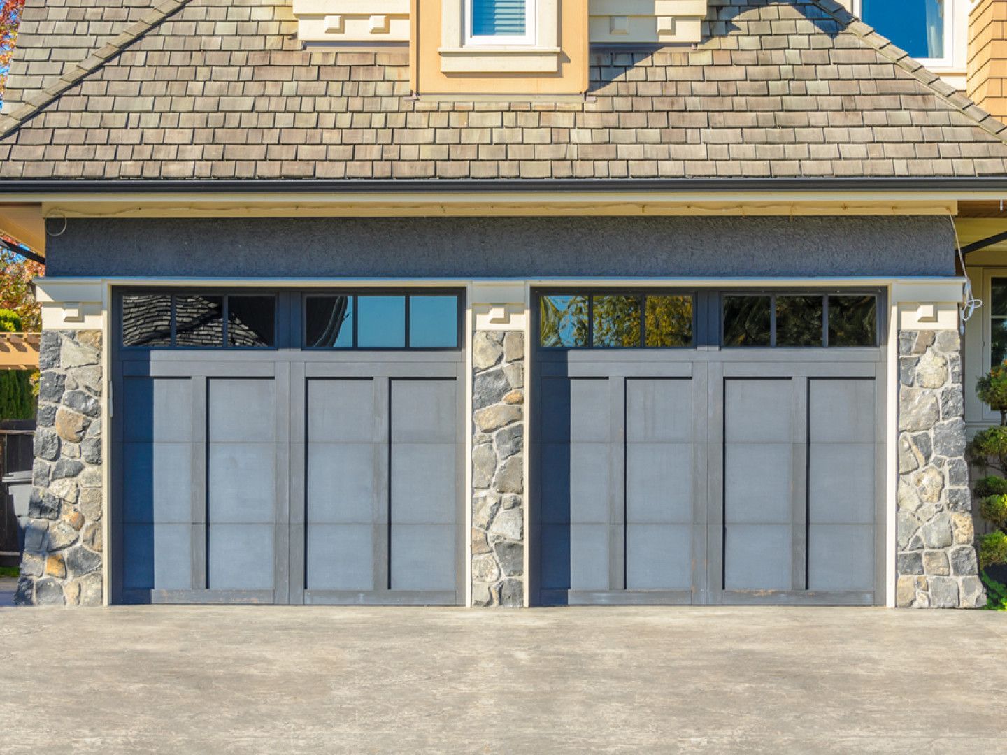 A large garage with a slate roof and a stone wall.
