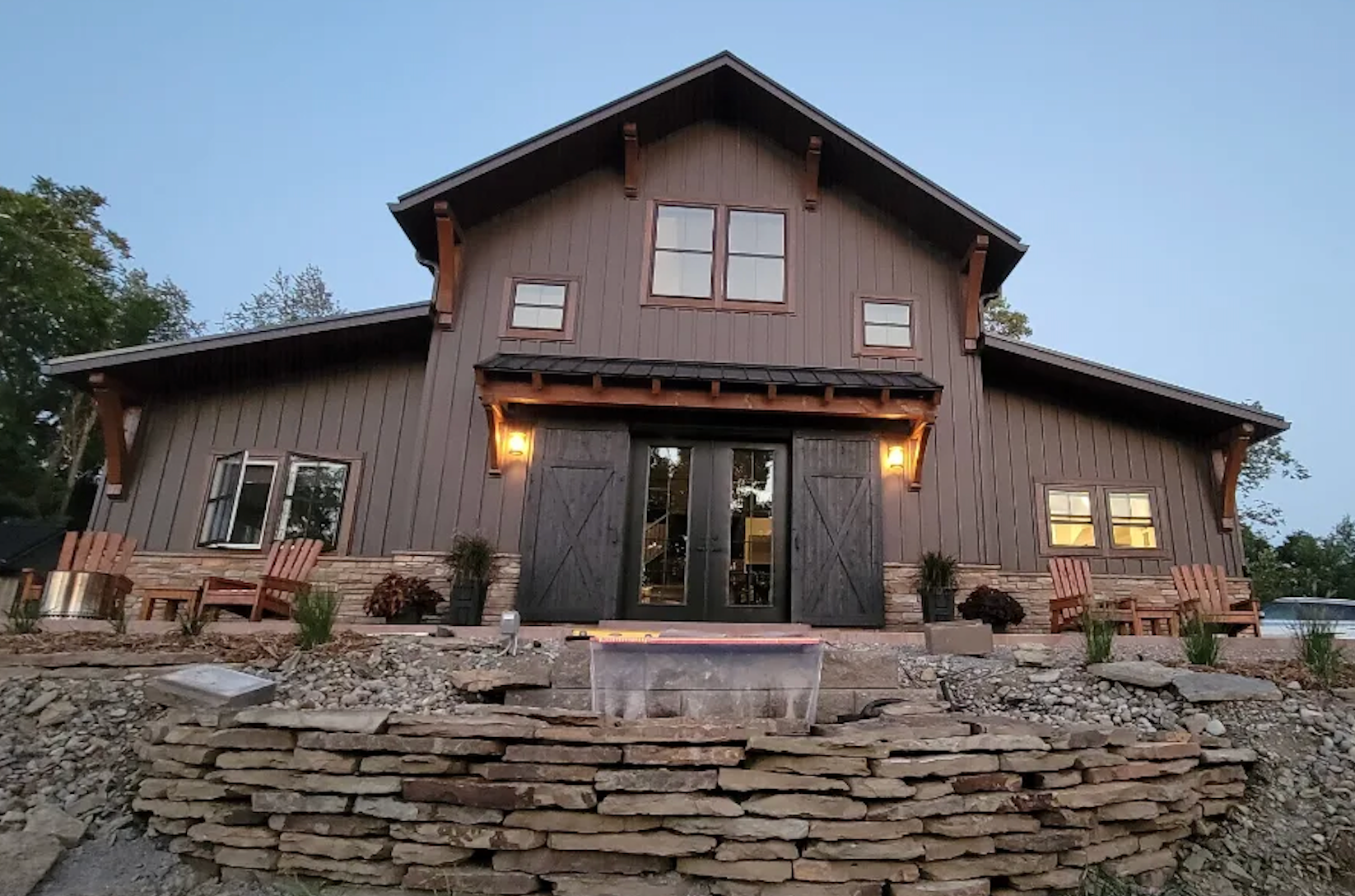Barndominium with wood siding, country barn sliding doors, and stone fountain