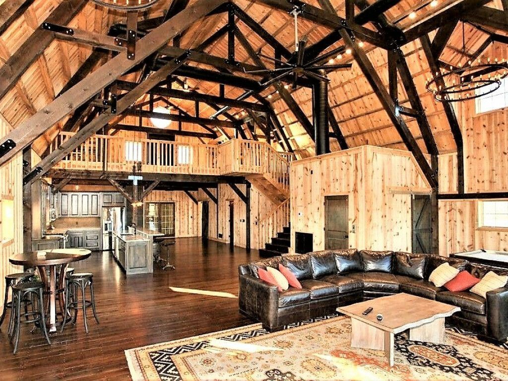 A living room in a barn with a couch , table and rug.