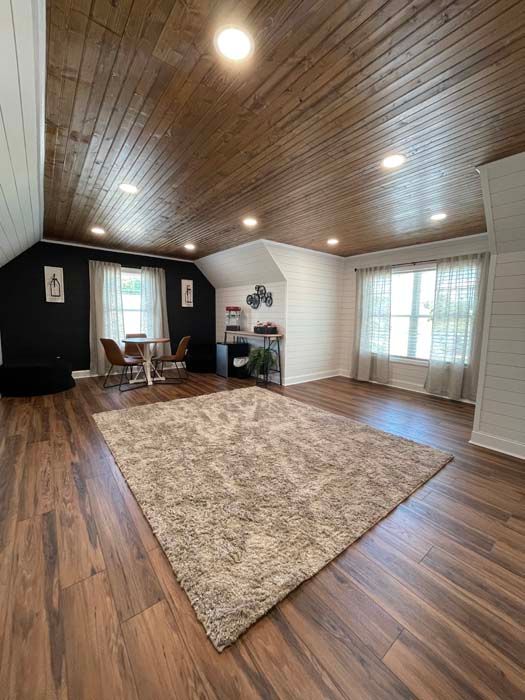 A living room with hardwood floors , a rug and a wooden ceiling.