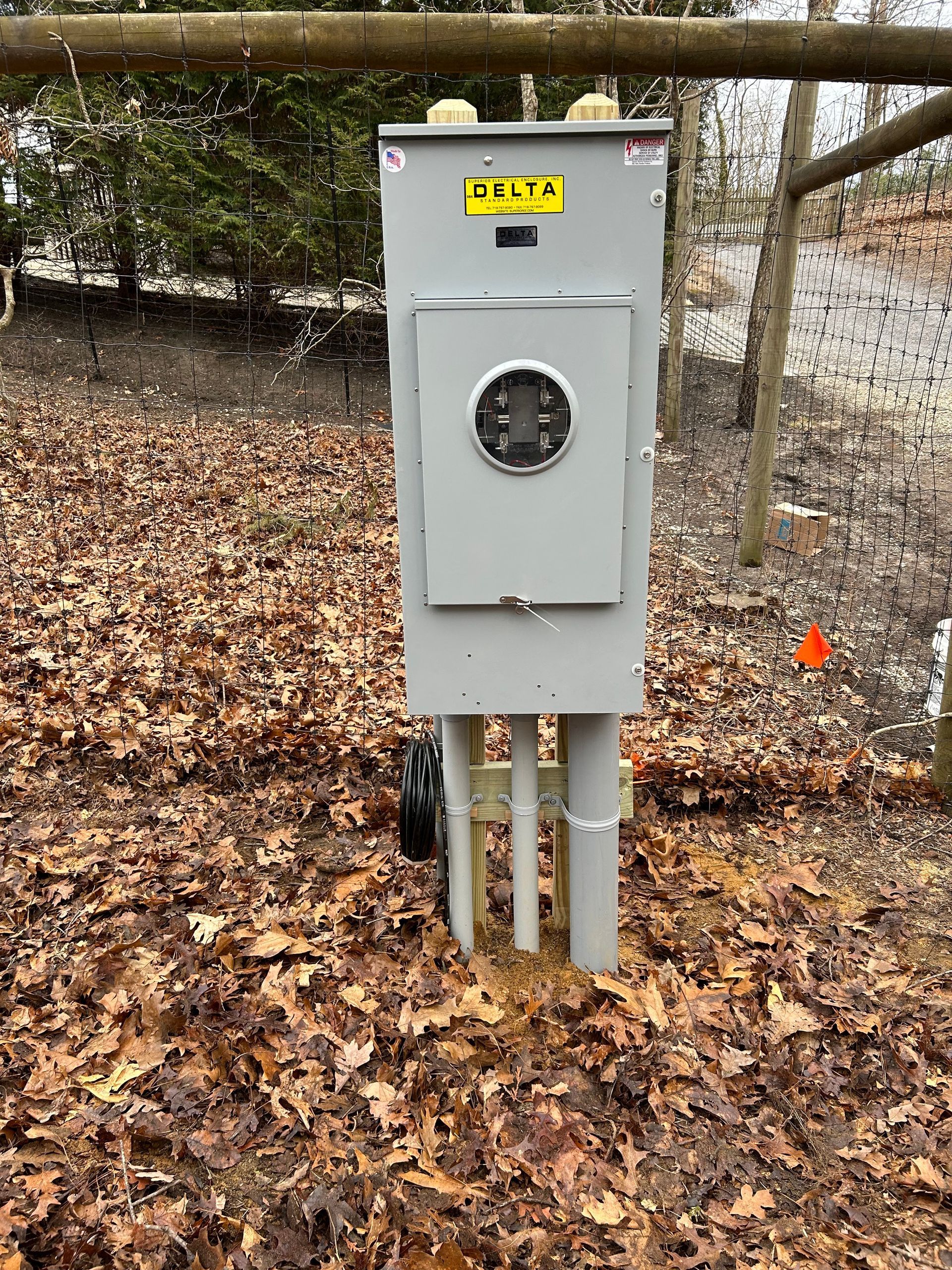 A large electrical box is sitting on top of a pile of leaves.