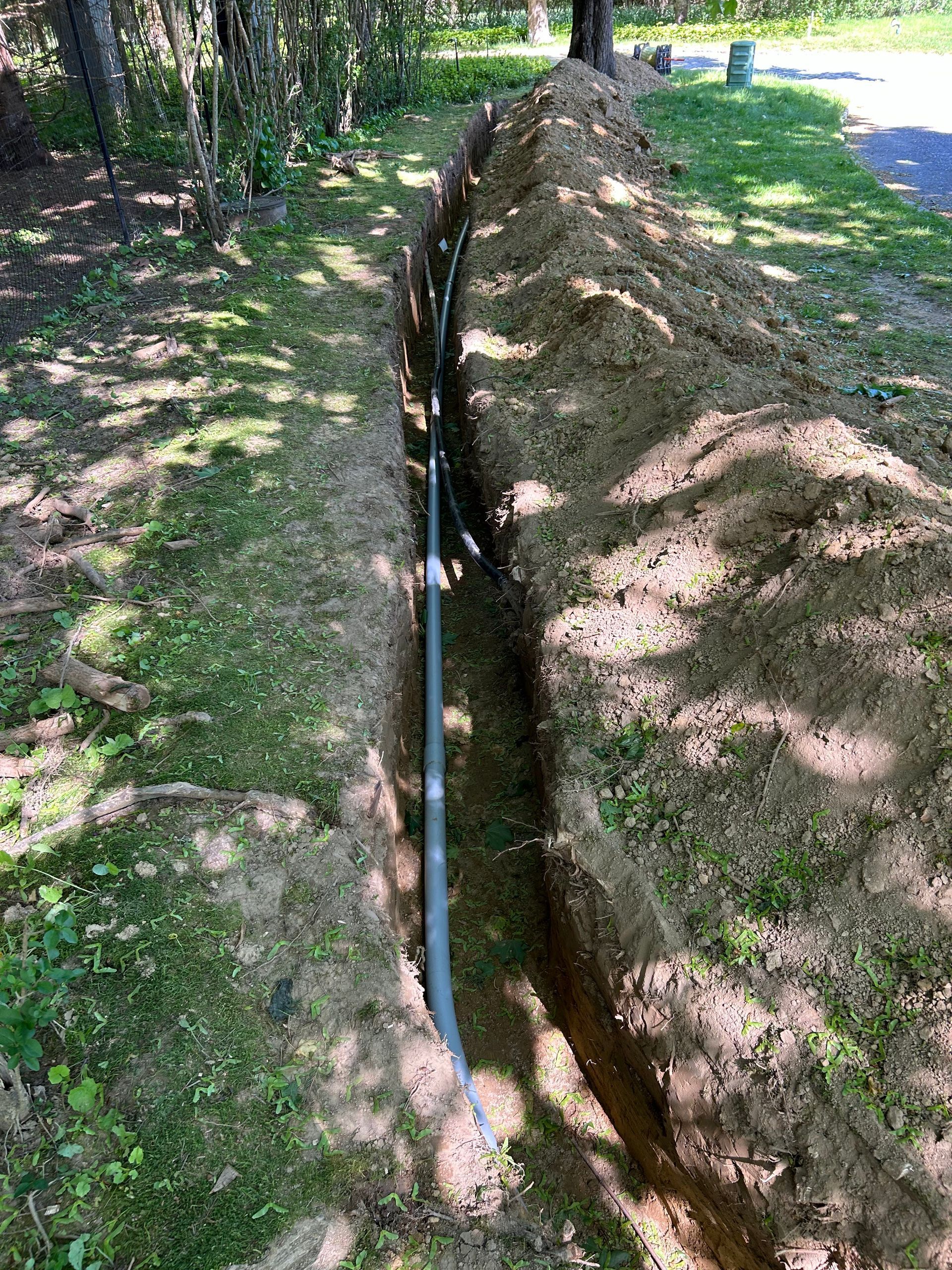 A pipe is being installed in a trench in the dirt.
