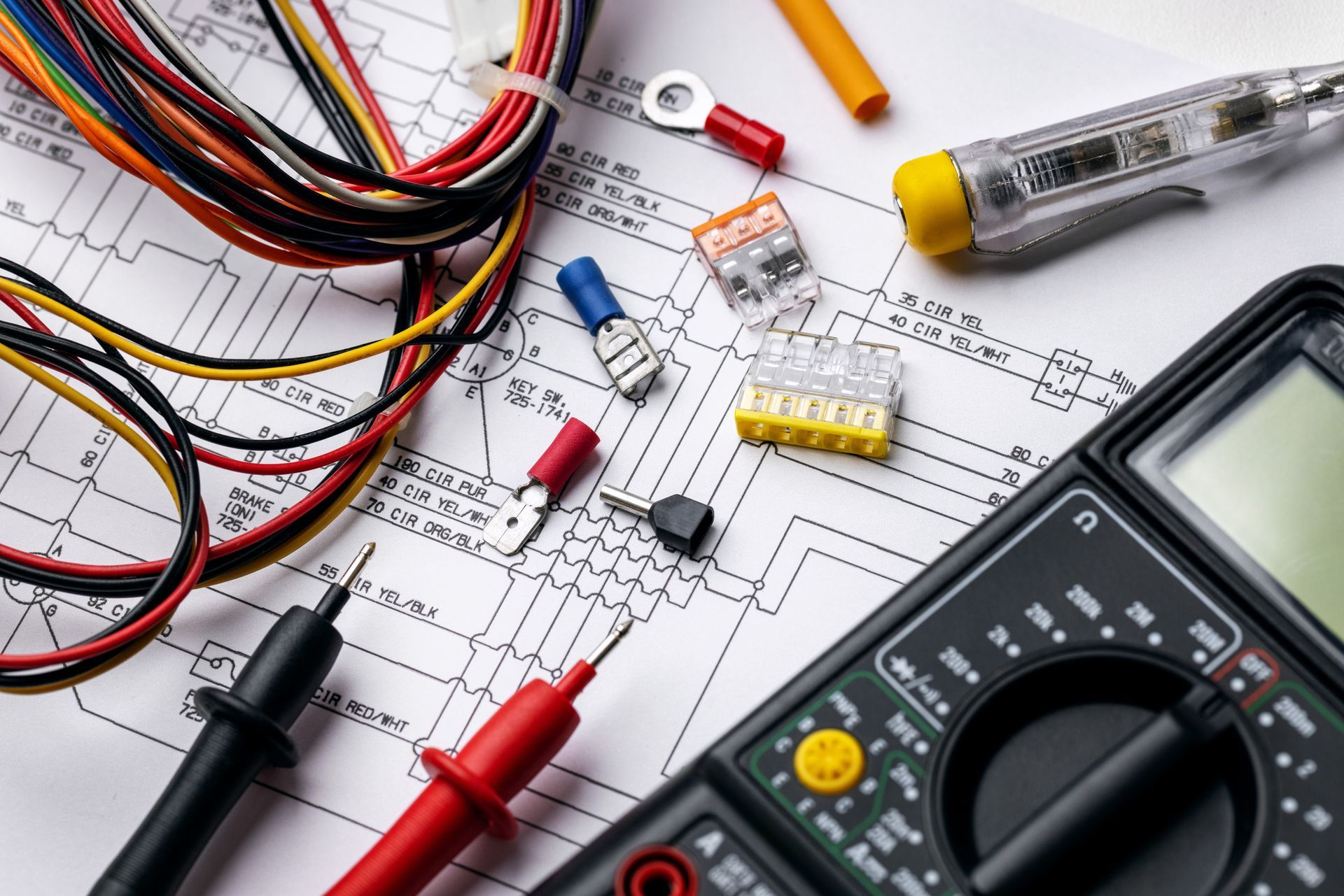 Multimètre, fils et composants électroniques sur un établi de schématisation de circuit