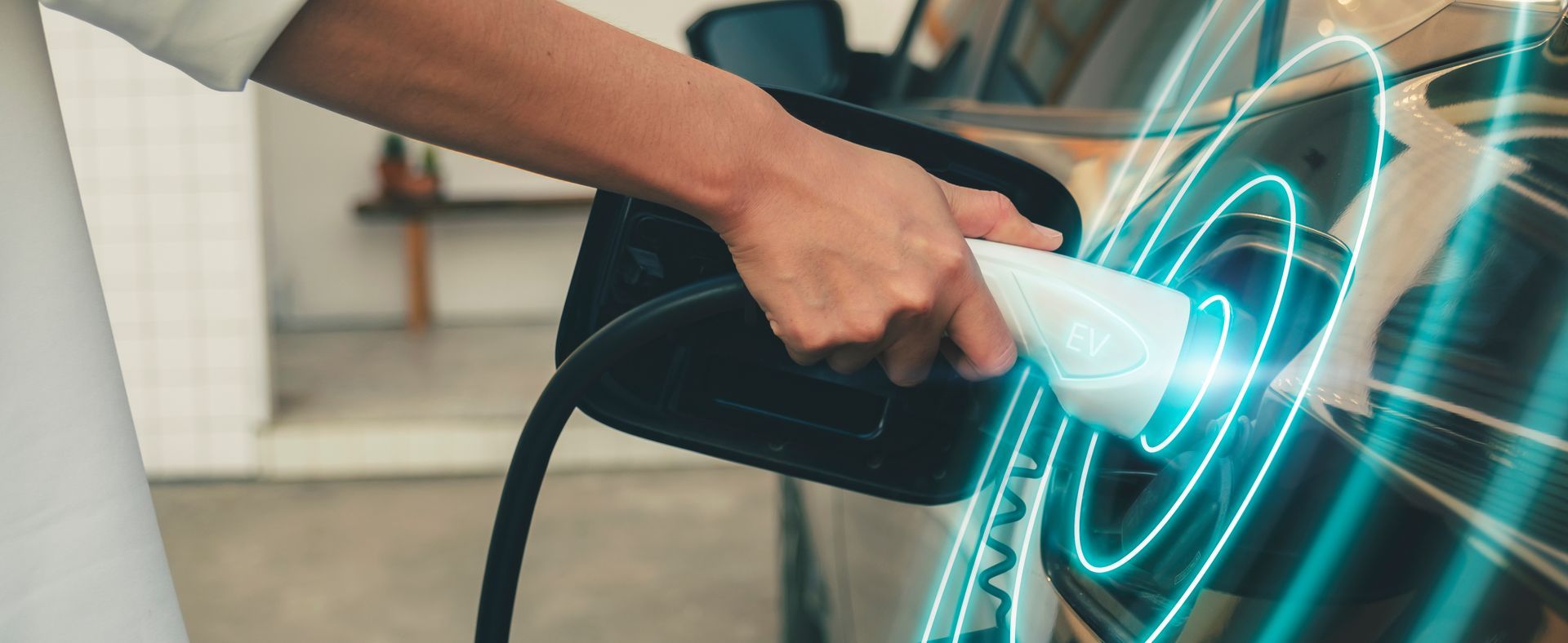 Une personne charge une voiture électrique à une borne de recharge.