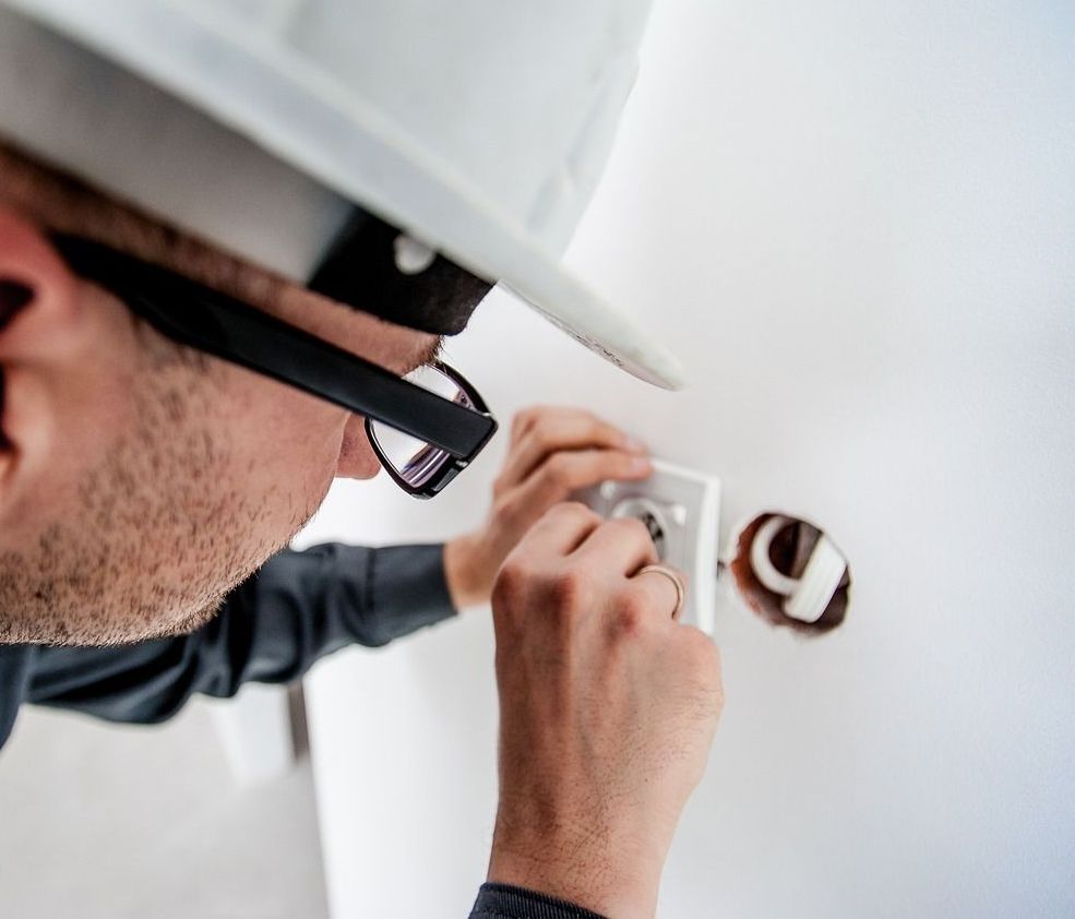 Un homme portant un casque et des lunettes travaille sur un mur.