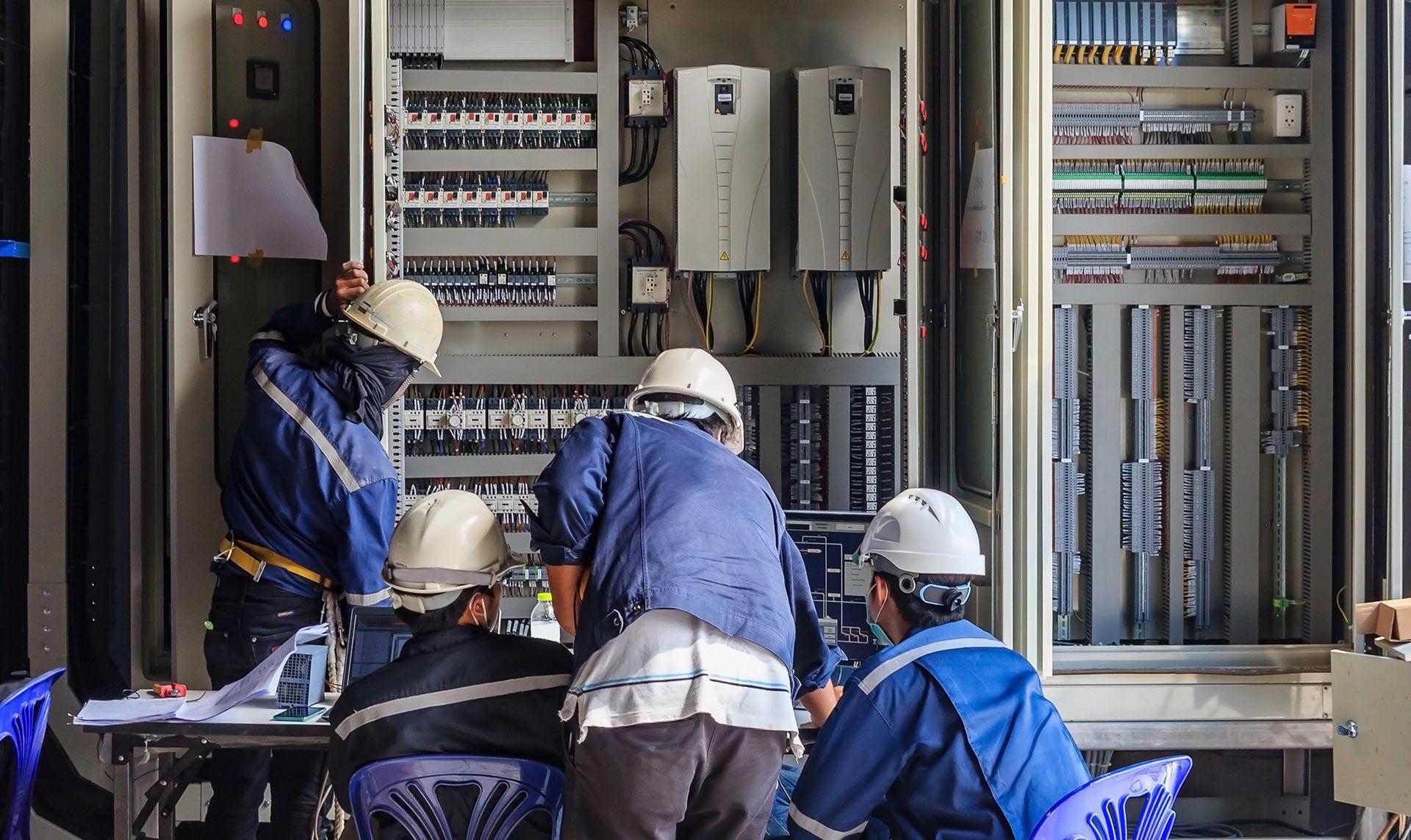 Un groupe d'hommes travaille sur un coffret électrique.