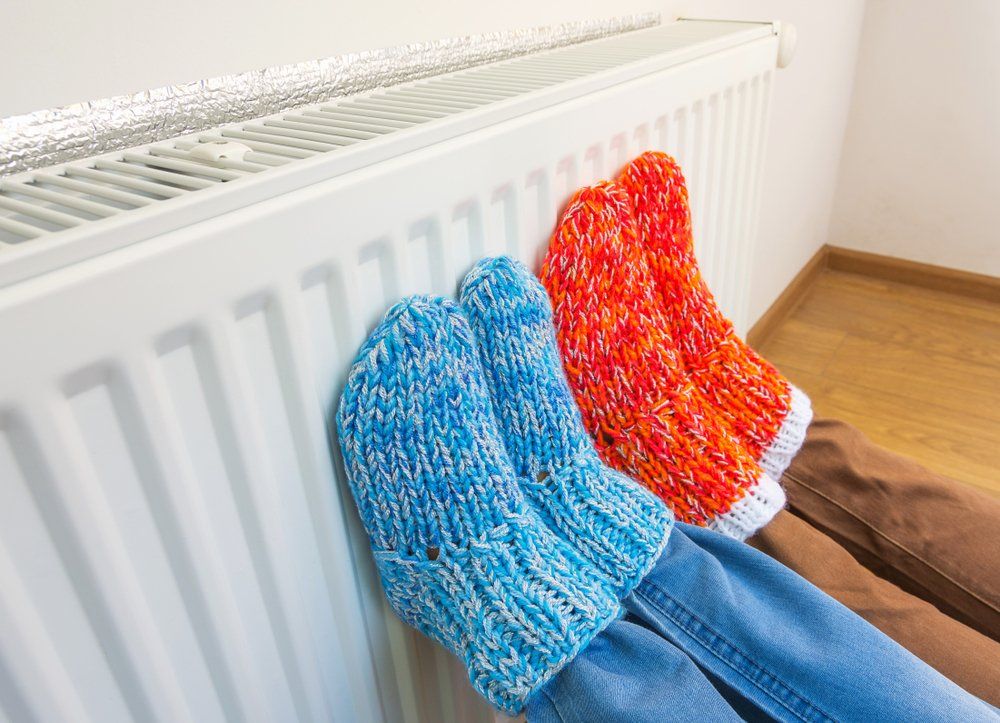 Une paire de pieds portant des chaussettes tricotées se réchauffent sur un radiateur.