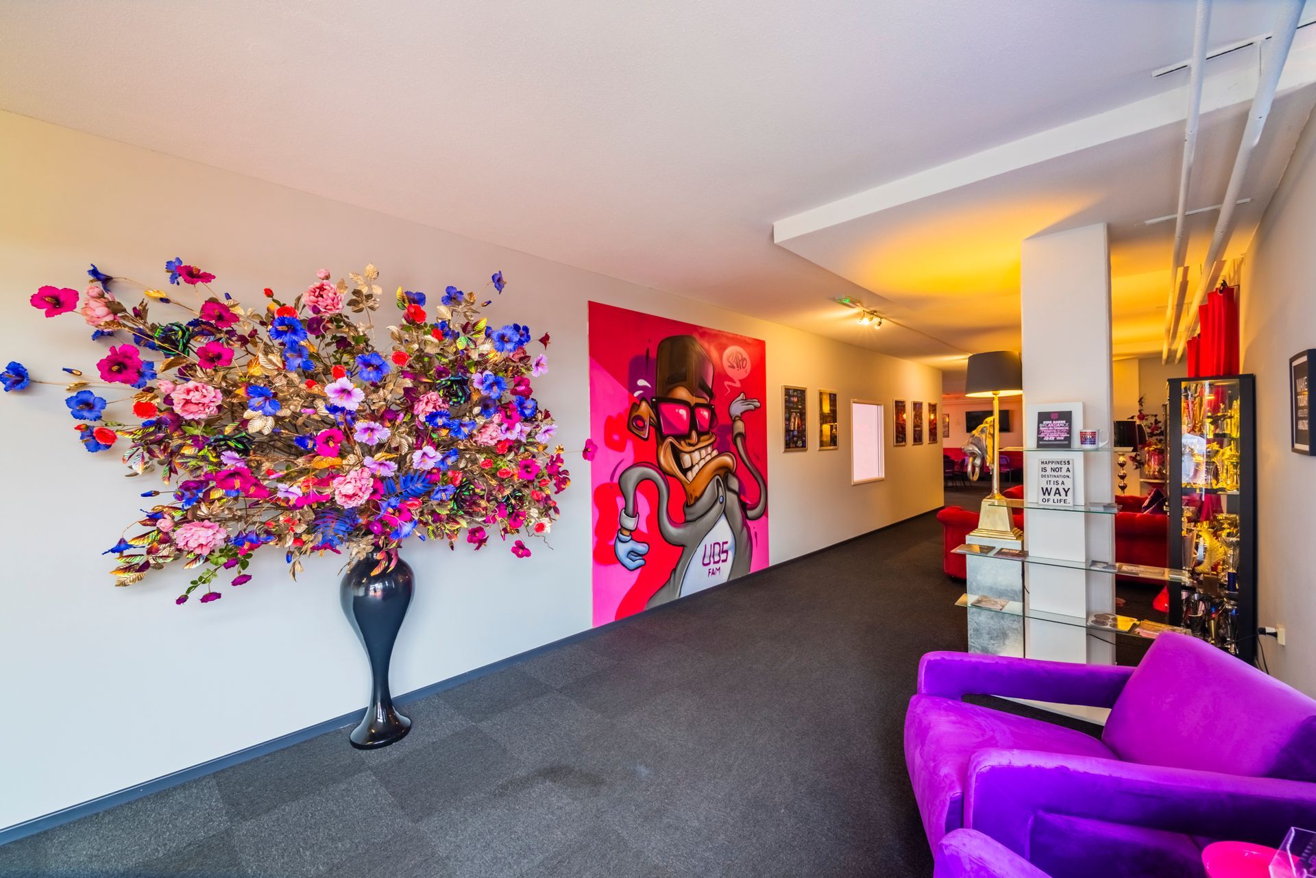 Een kleurrijke lobby met bloemenmuurdecoratie, een paarse stoel en een hal met een vrolijke inrichting.