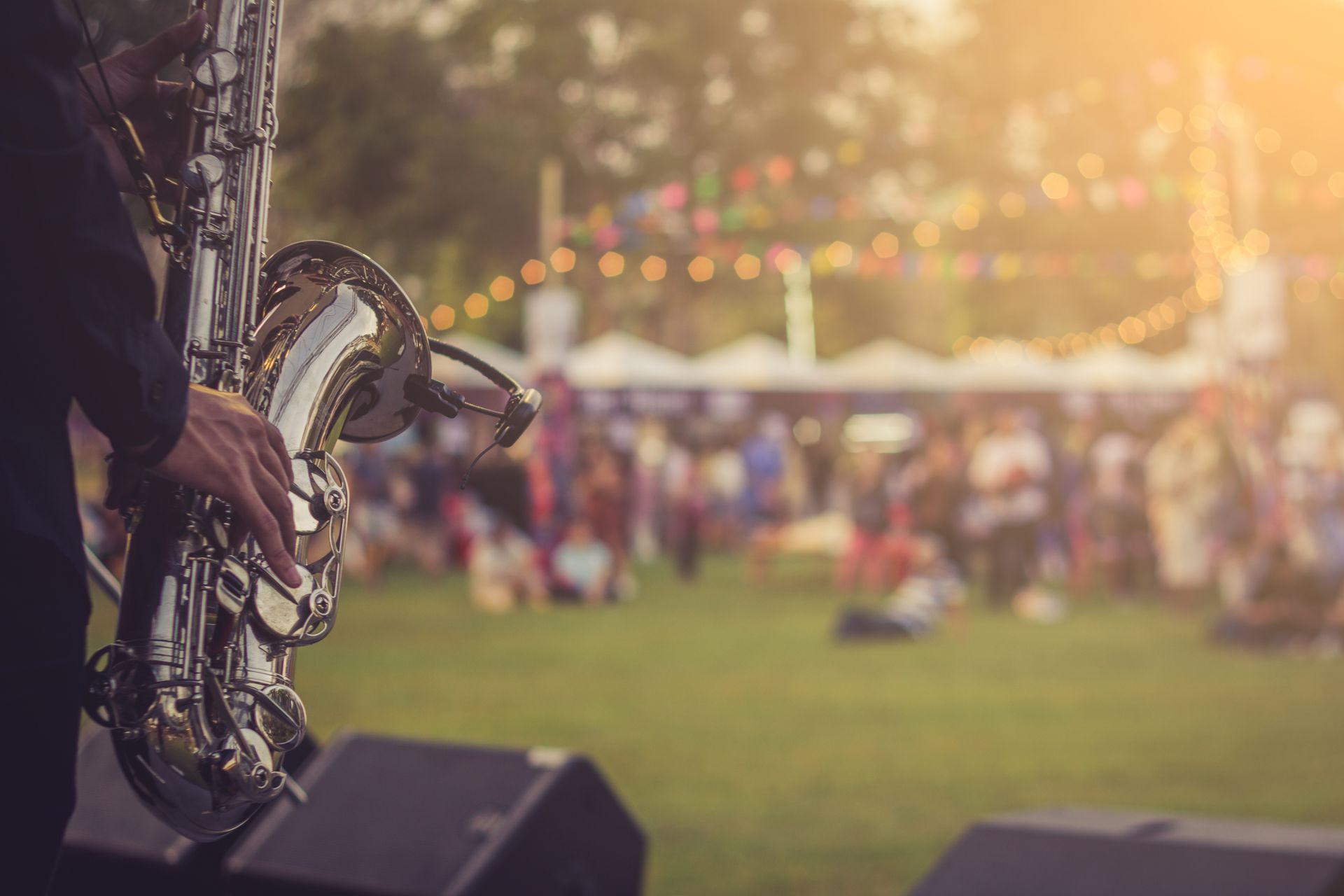 A man is playing a saxophone in front of a crowd at a festival.