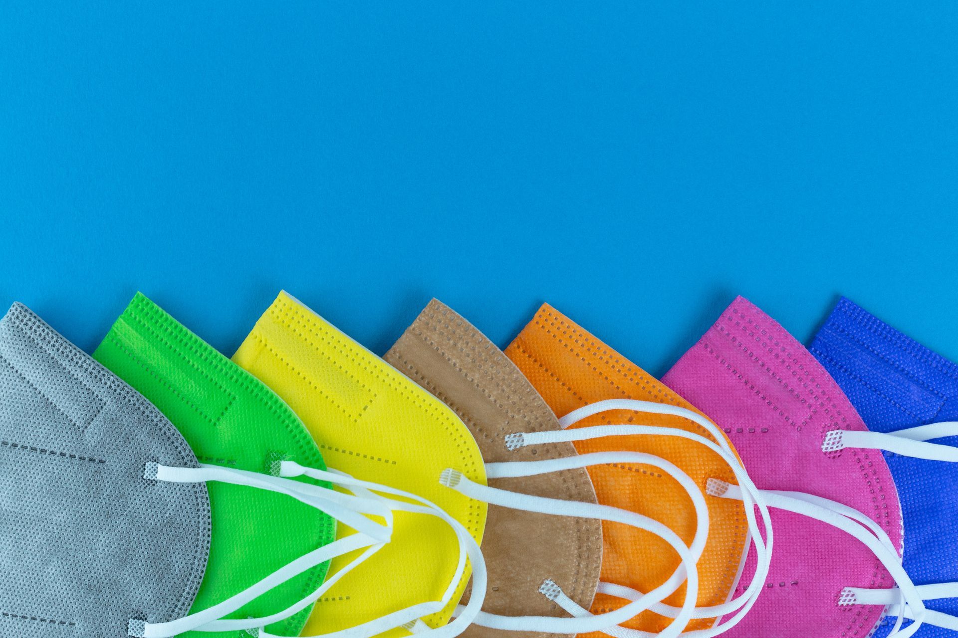 Row of colorful face masks on a blue background.