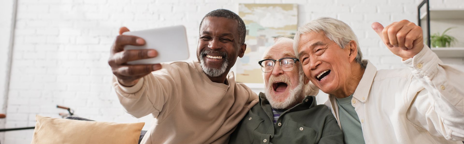 Three older men are taking a selfie with a cell phone.