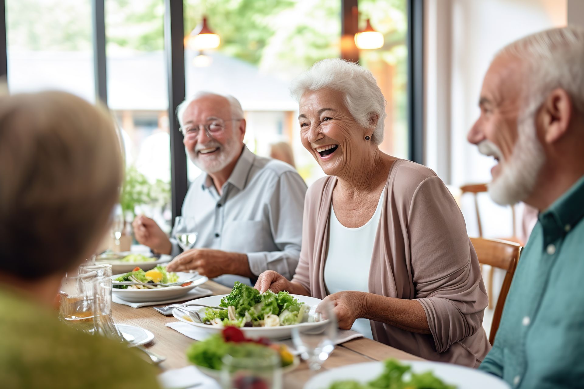 Group of smiling seniors enjoying a meal at a table indoors.