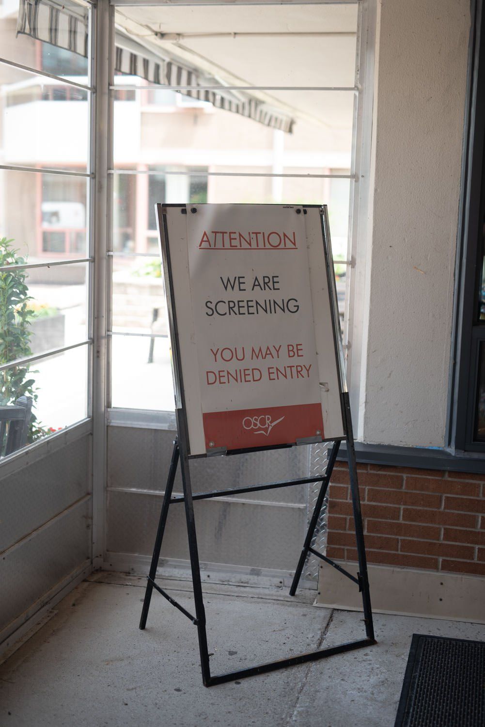 A sign that says attention we are screening you may be denied entry