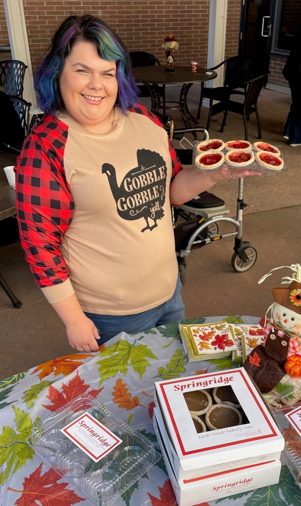A woman is standing in front of a table holding a box of cookies.