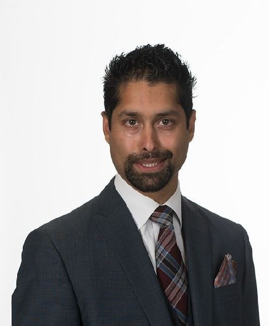 Man in a suit, smiling, looking at the camera. White background.
