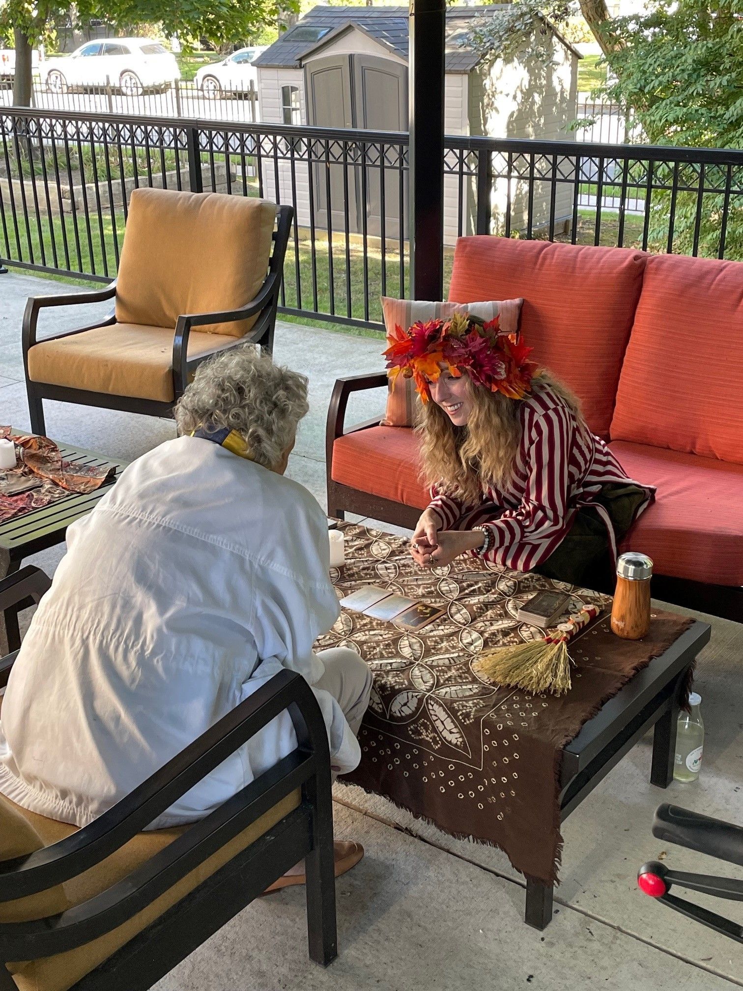 Two women are sitting at a table on a porch.