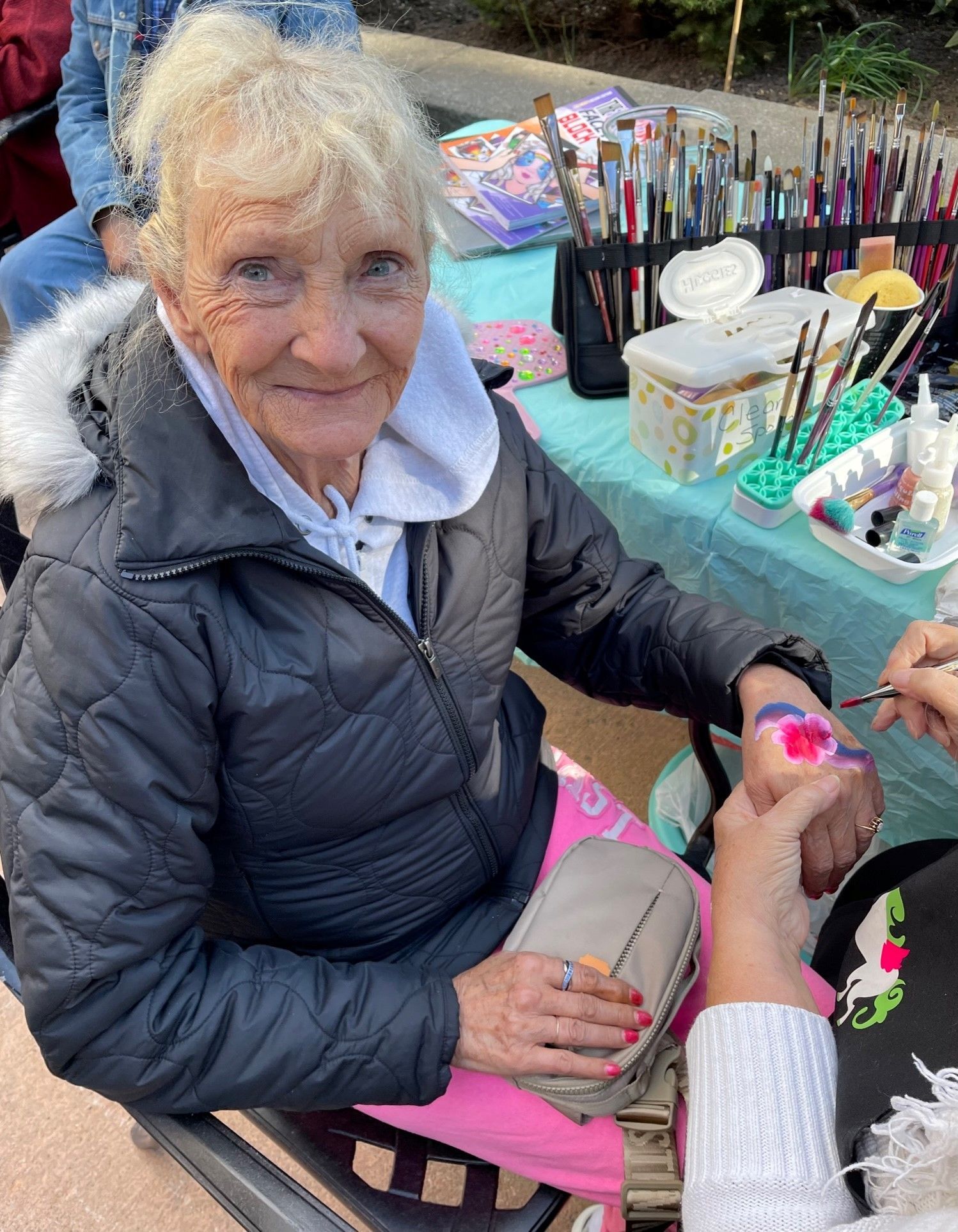 A woman in a wheelchair is getting her face painted.
