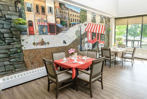 Restaurant dining area with mural of a European street scene, tables set for dining.
