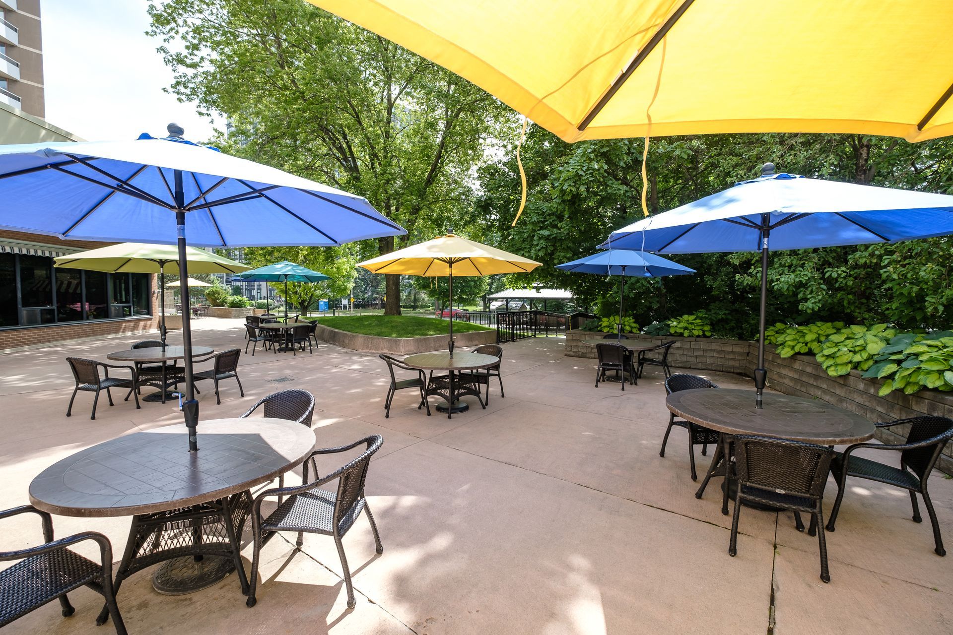 Outdoor patio with round tables and umbrellas in various colors.