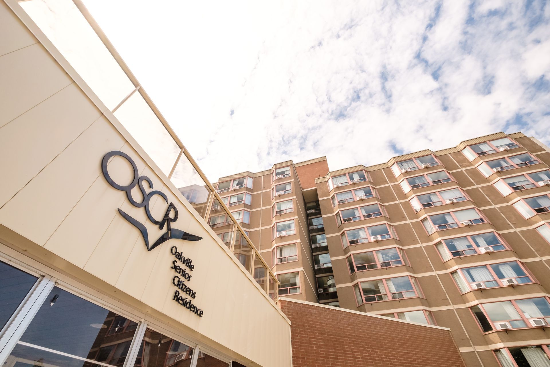 OSCR sign on building entrance. Tall brick building with windows and blue sky.