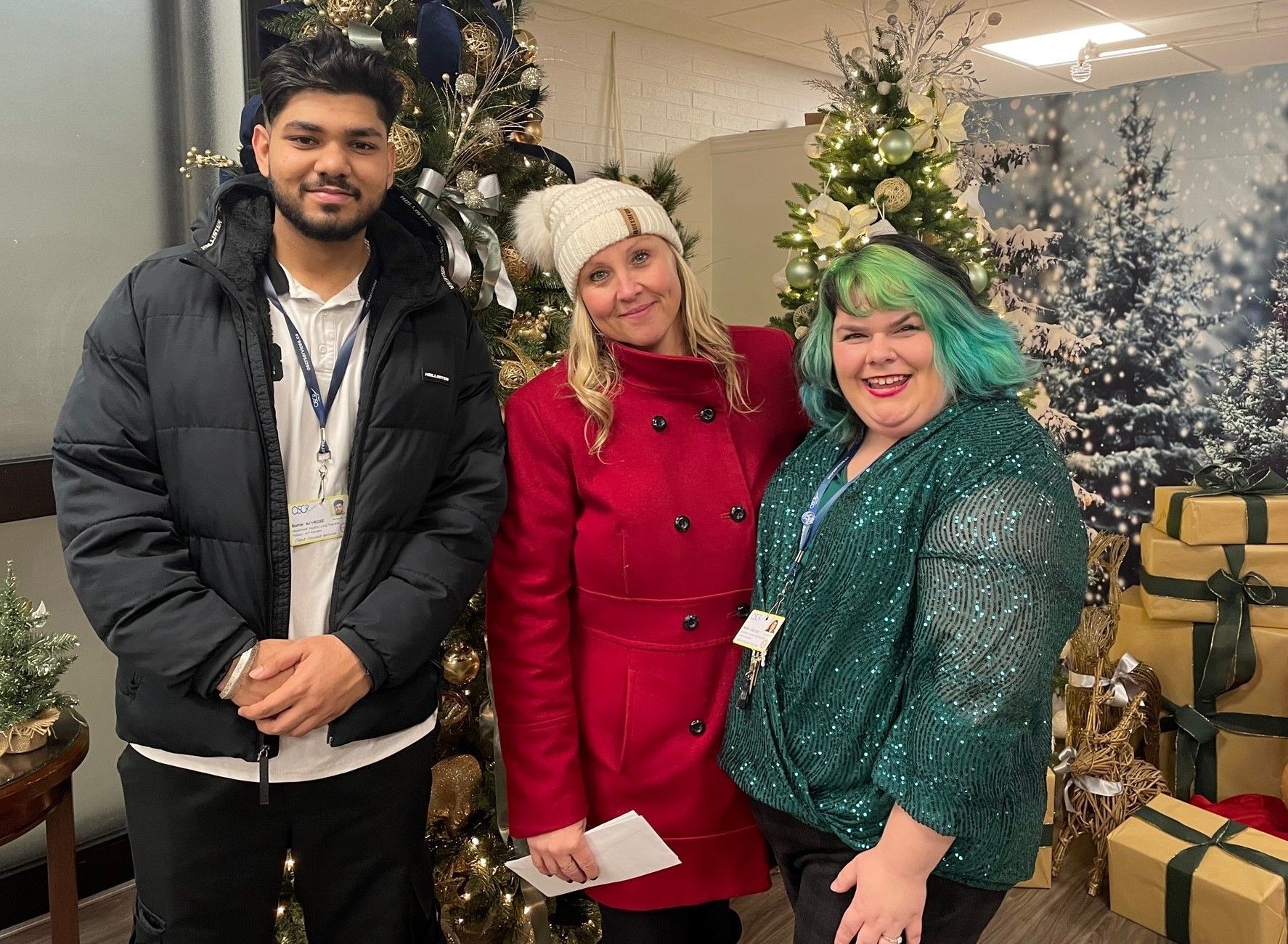 A man and two women are posing for a picture in front of a christmas tree.