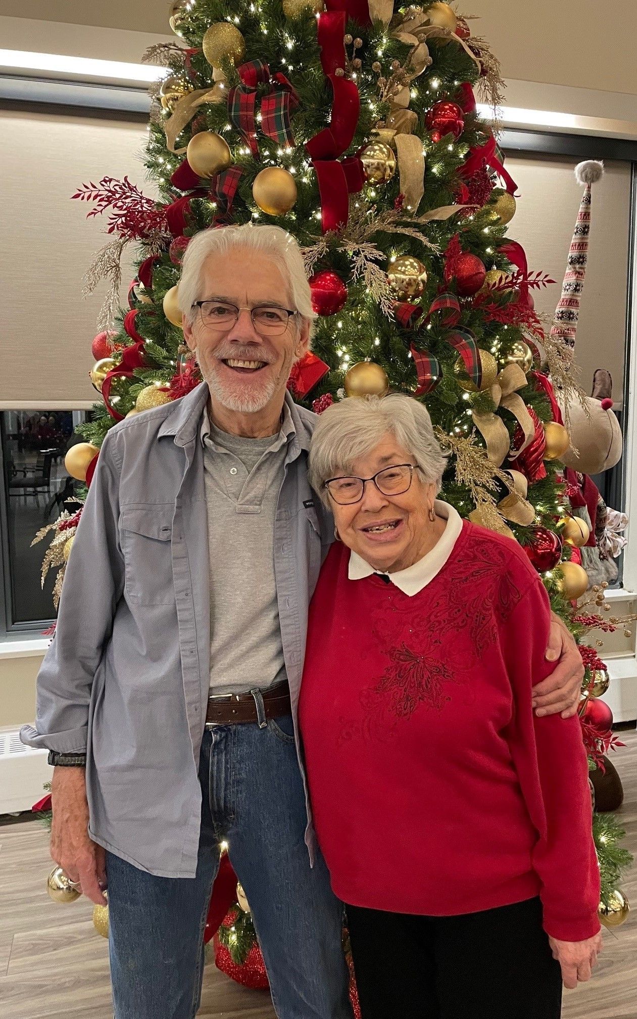 A man and woman are posing for a picture in front of a christmas tree.