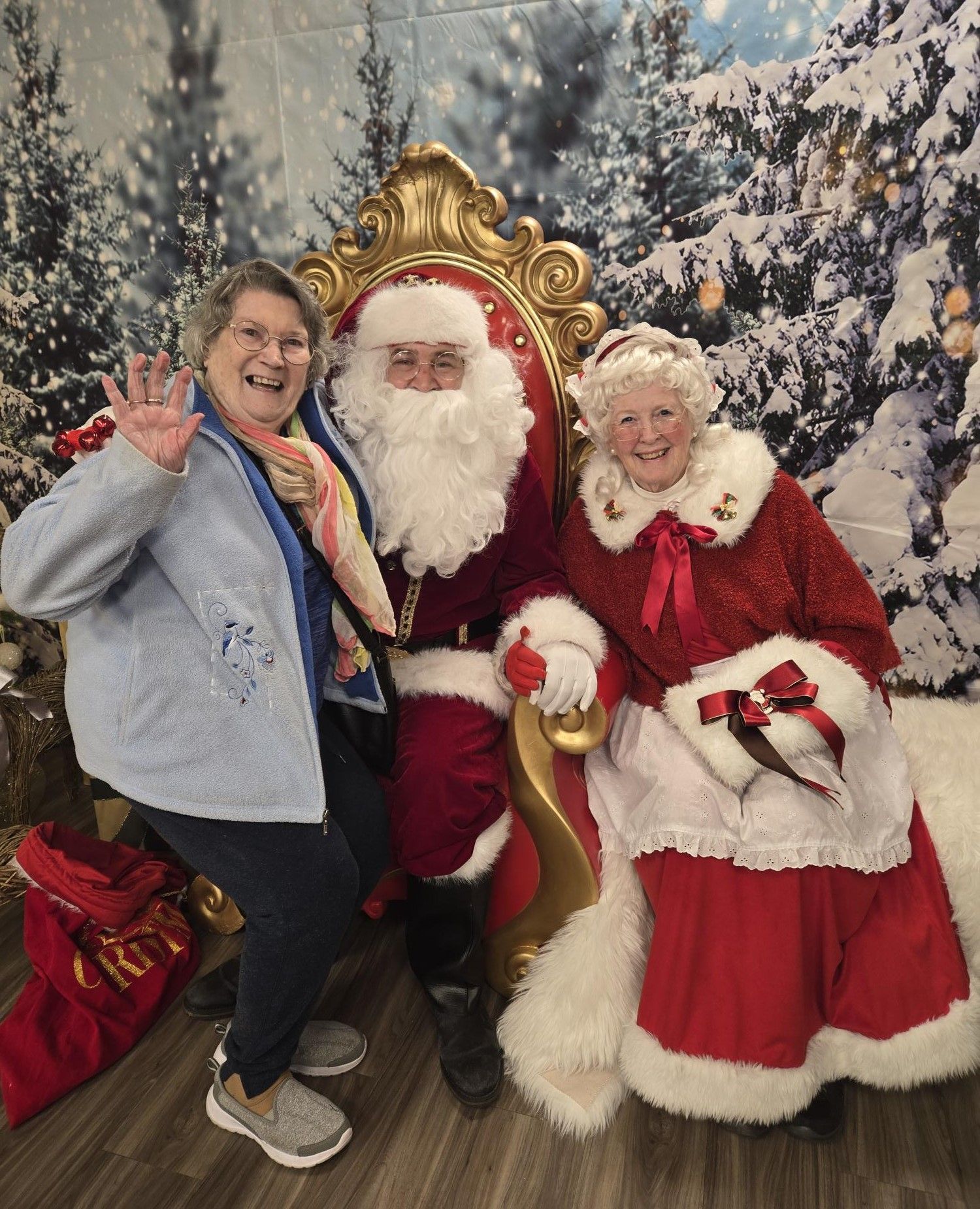 Two women are posing for a picture with santa claus and mrs. claus.