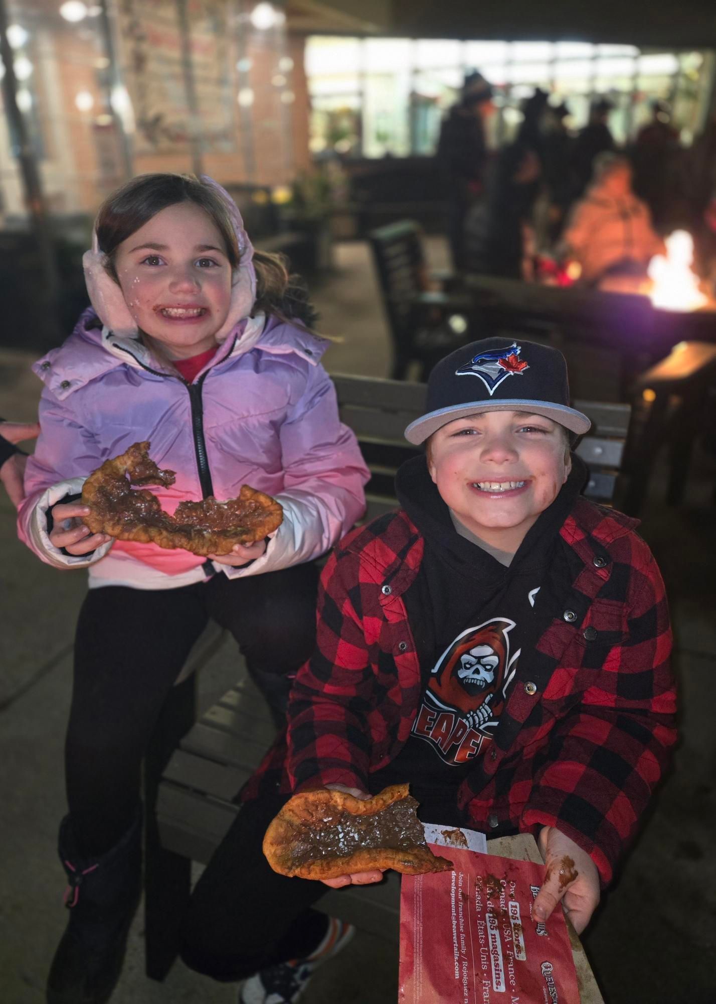 A boy and a girl are sitting next to each other eating food.