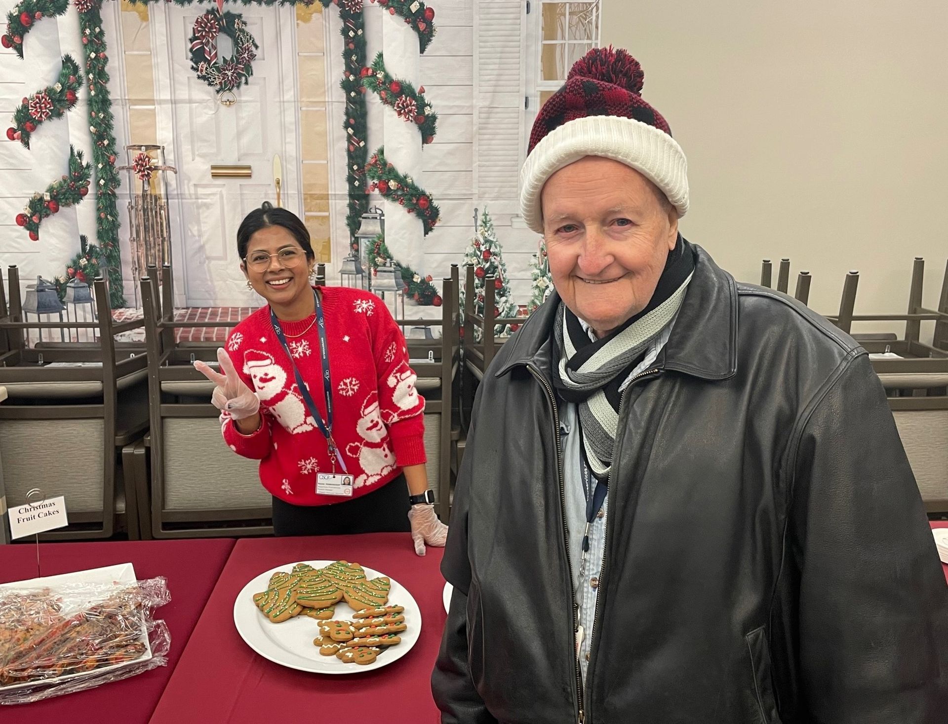 A man and a woman are standing in front of a table with a plate of cookies on it.