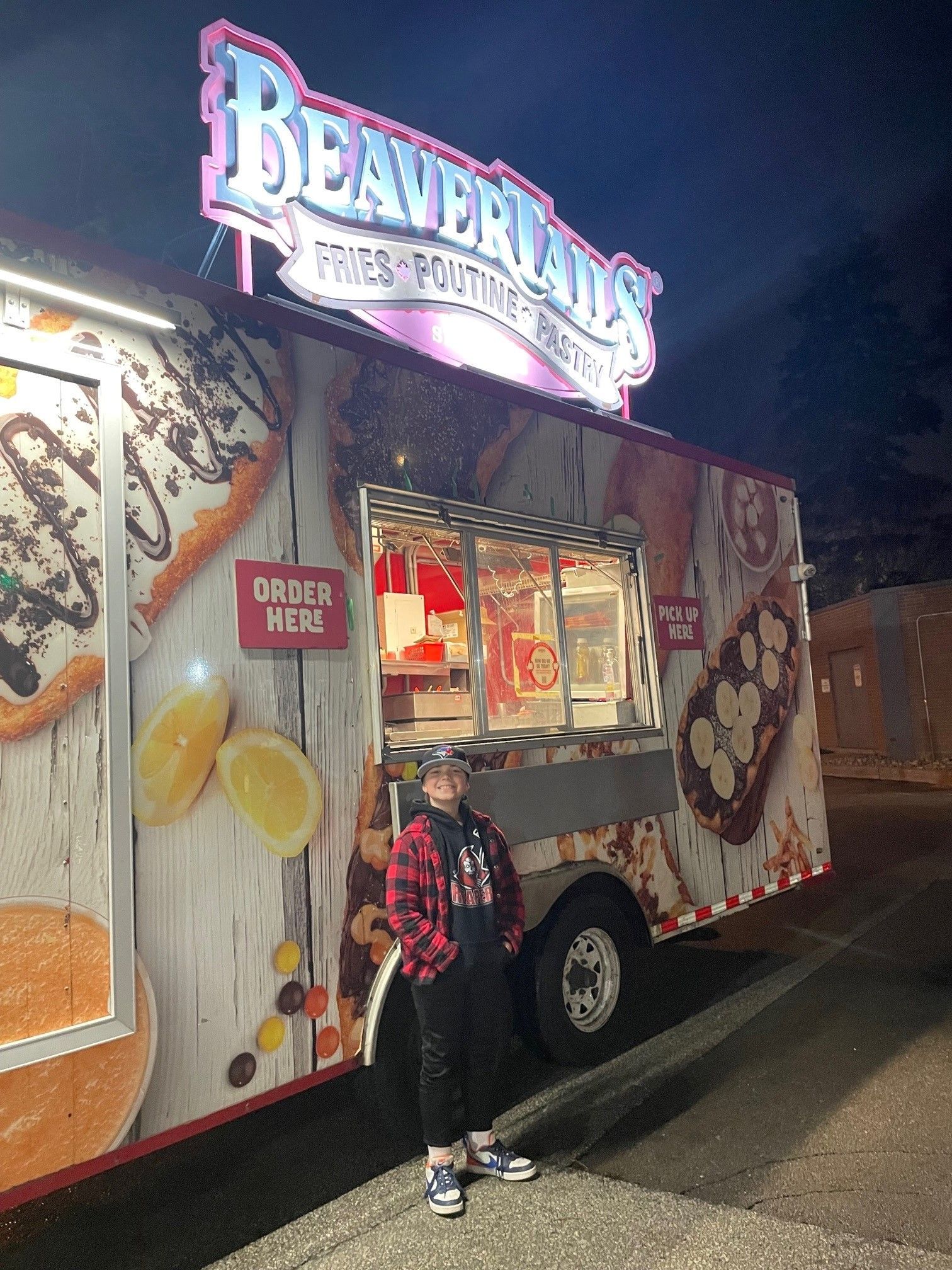 A boy is standing in front of a food truck.