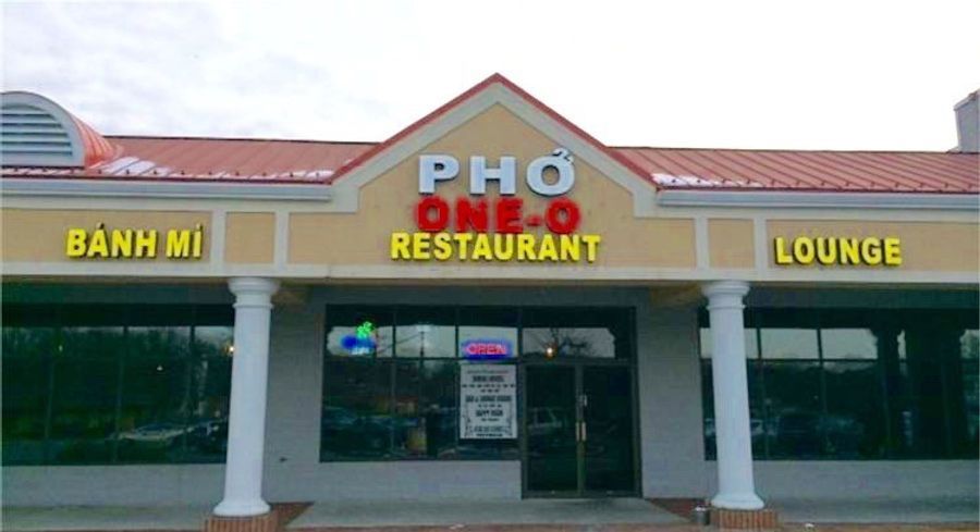 Front of a pho restaurant with yellow “Banh Mi” and “Lounge” signs, red-roofed entrance, and white columns