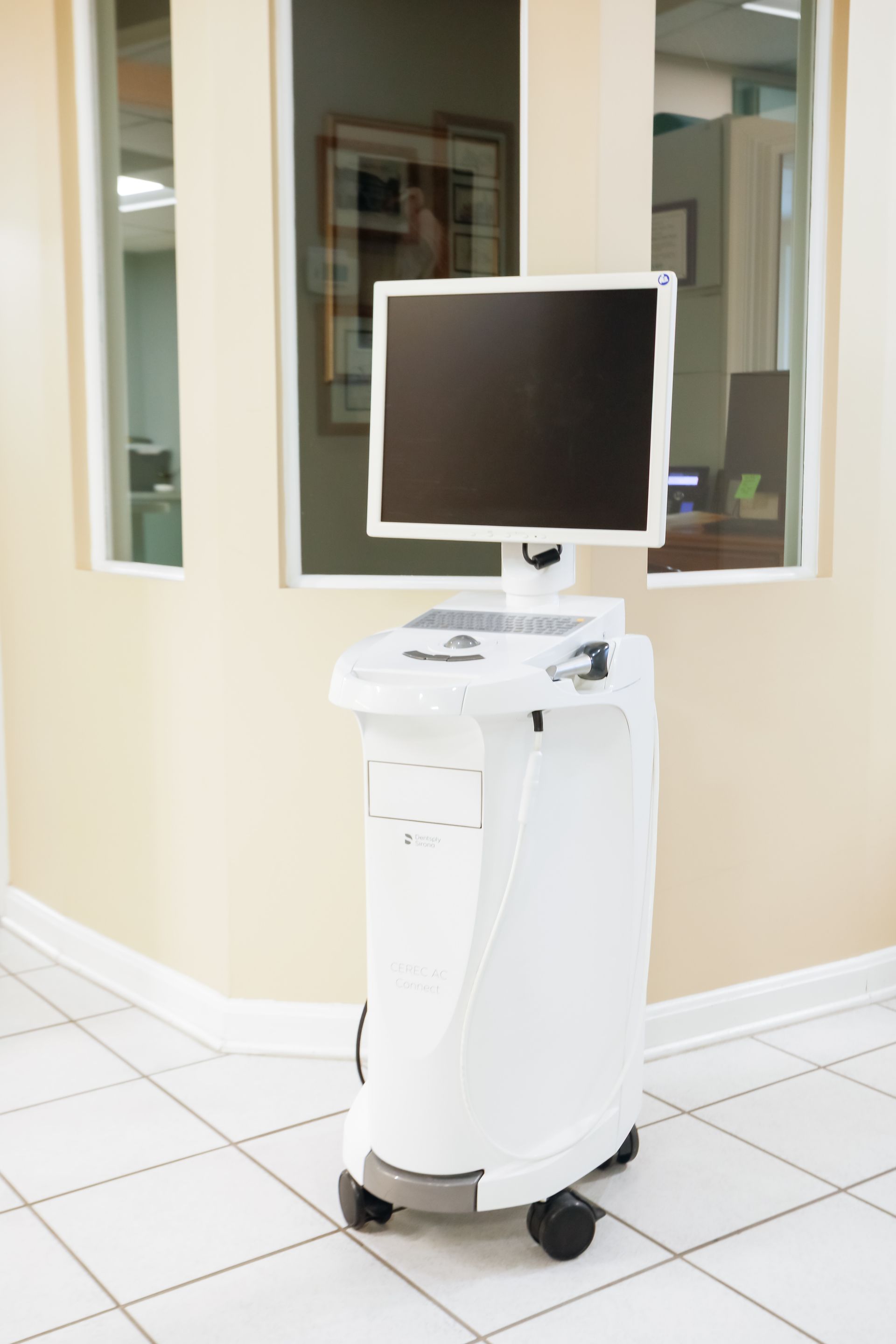 Medical cart with a monitor in a tiled hallway outside office windows