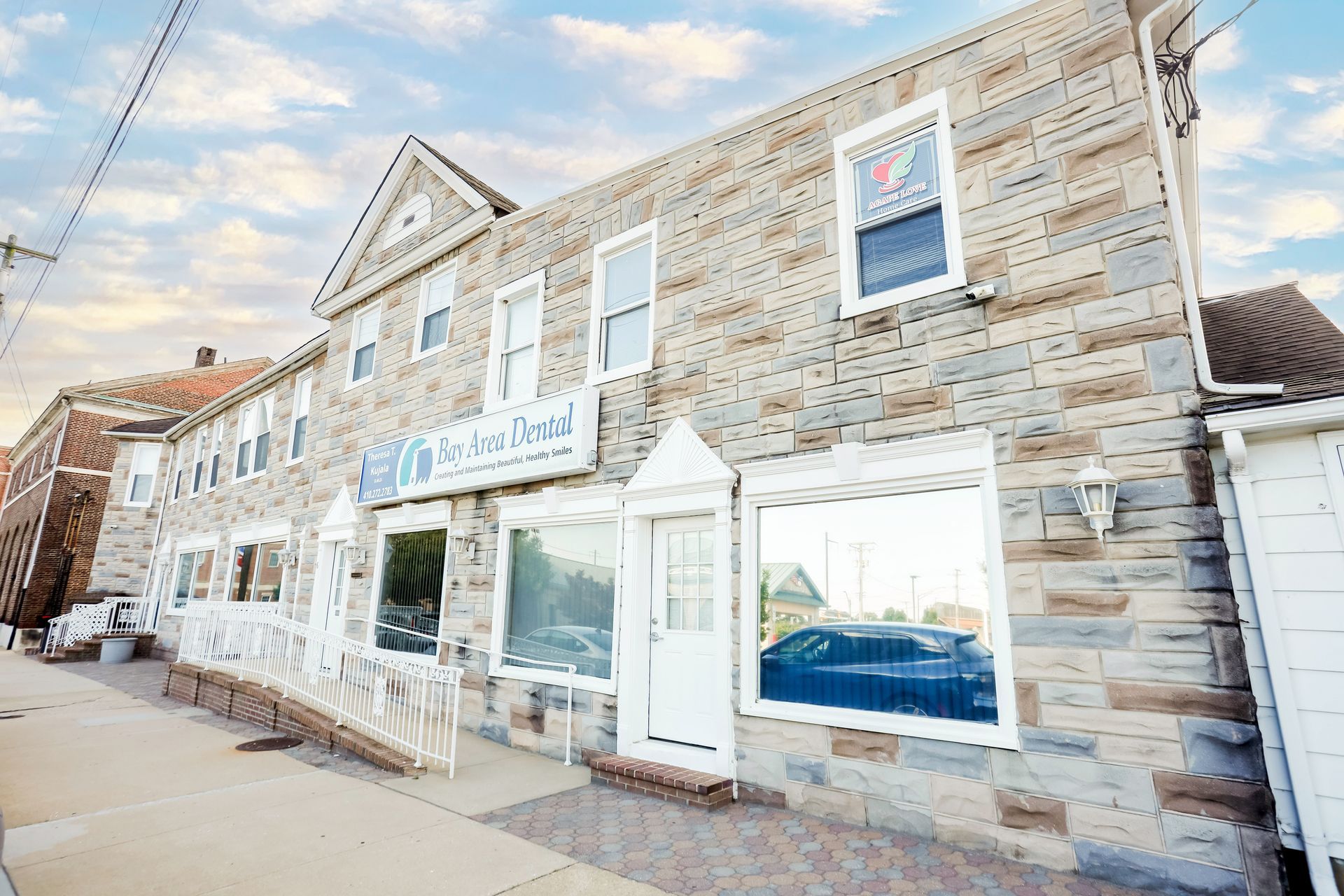 Stone storefronts along a quiet street, with white trim and large display windows under a bright sky