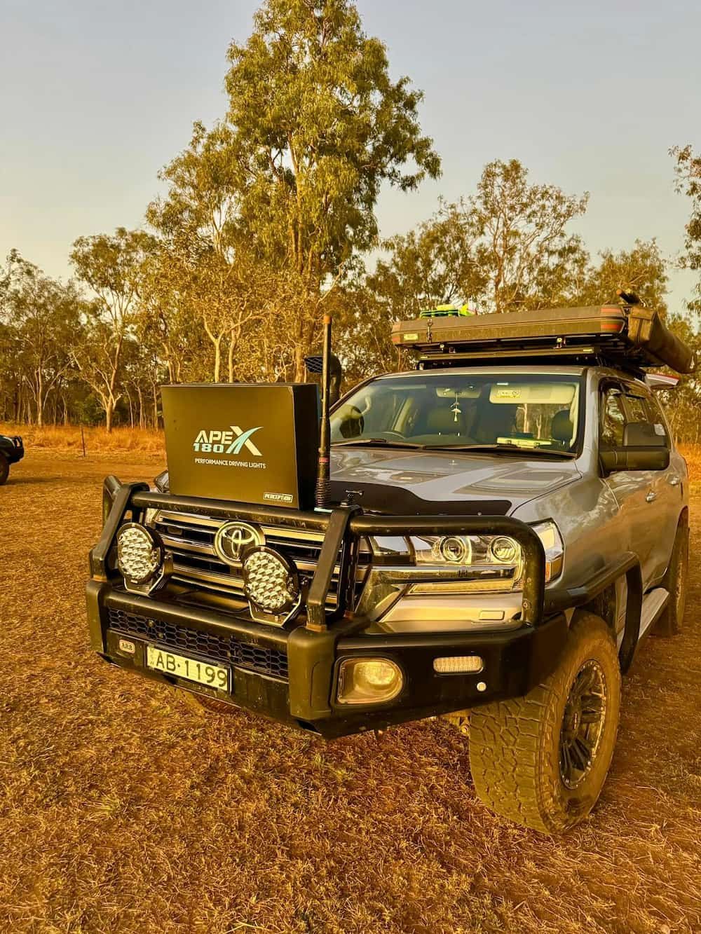 A Toyota Land Cruiser with A Tent on Top of It Is Parked in A Dirt Field — Bonetig's Mobile Towbars & Trailers In Oak Flats, NSW